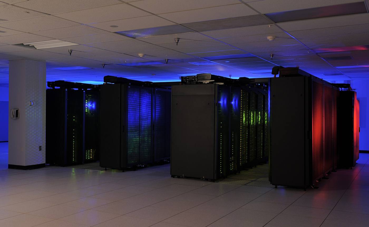Rows of supercomputer racks standing in a machine hall.