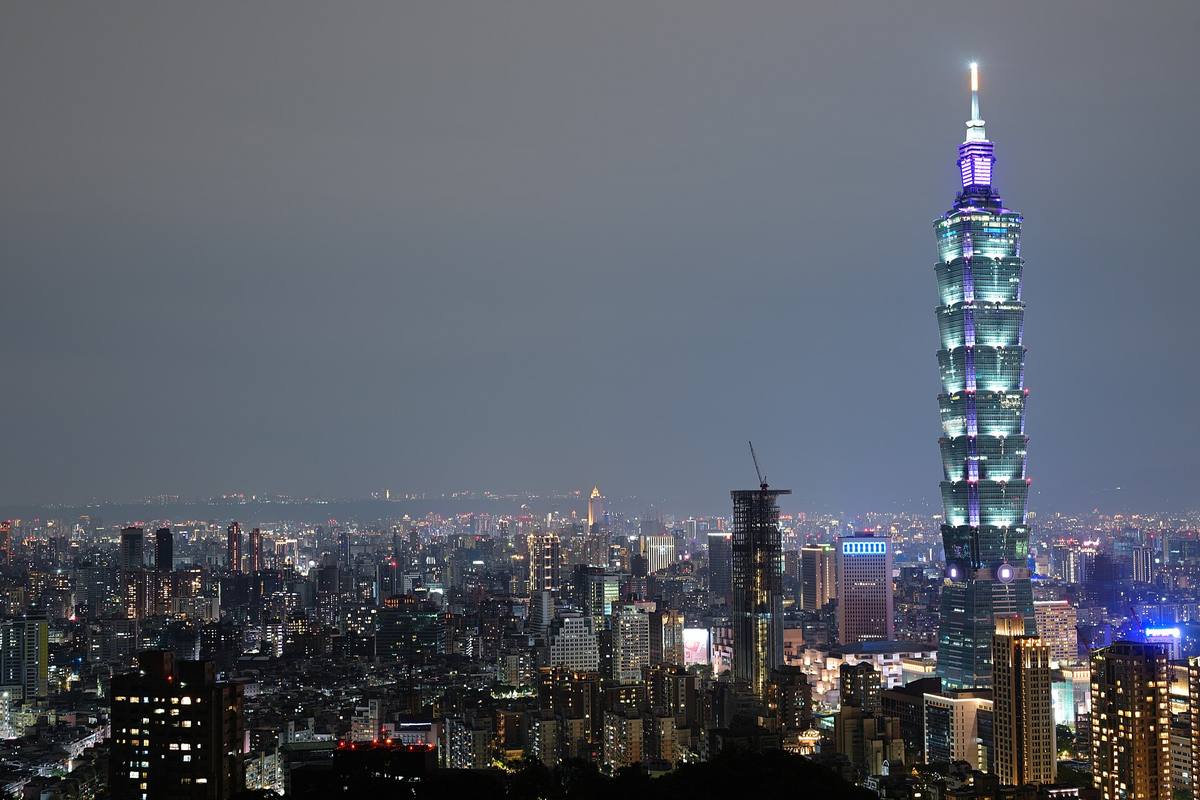 Night skyline of Taipei City with the Taipei 101 tower rising above a grid of lit streets.